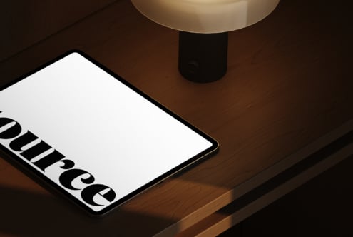 Tablet under brass pendant light on wooden desk with Source