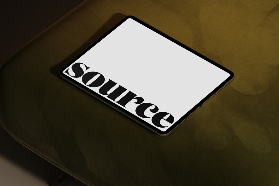 iPad on gold surface showing bold serif typography with eye logo