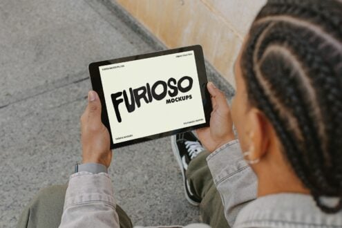 Person holding tablet with cream screen showing Furioso Mockups text logo