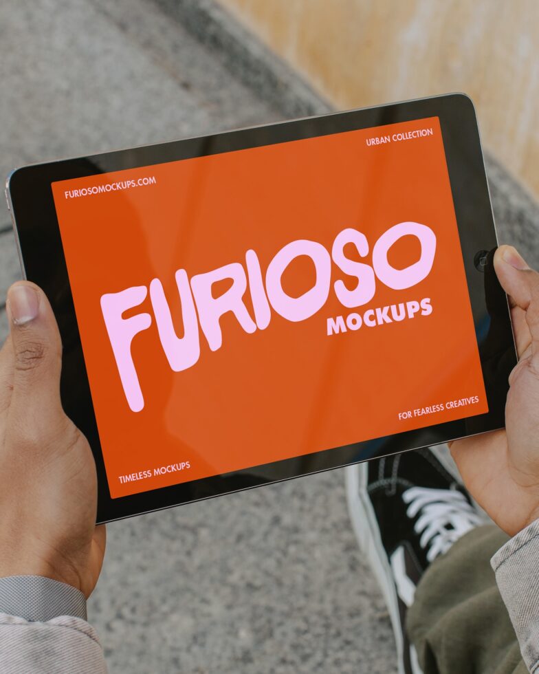 Tablet held up showing bright orange background with pink Furioso mockup