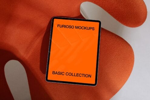 Tablet with orange screen on red textured surface surrounded by geometric shadows