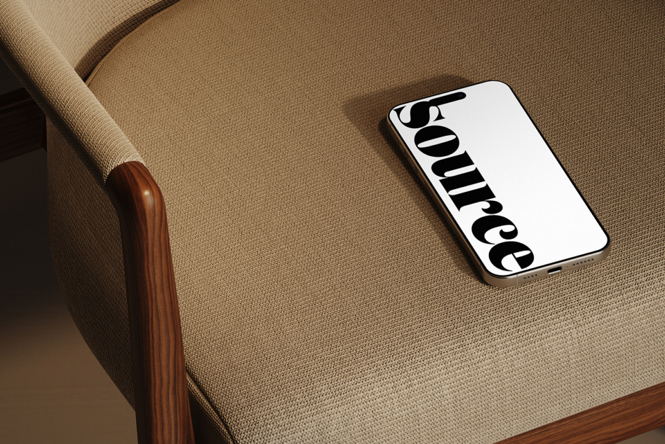 Smartphone resting on beige fabric armchair with wood frame detail