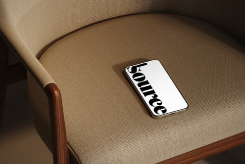 Phone lying on neutral linen sofa seat with wooden arm visible