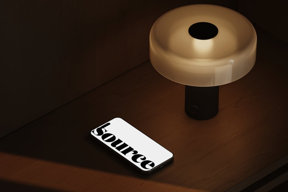 Smartphone with bold serif text on white screen next to brass table lamp