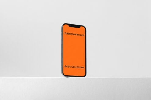 Smartphone standing upright showing orange mockup on white surface