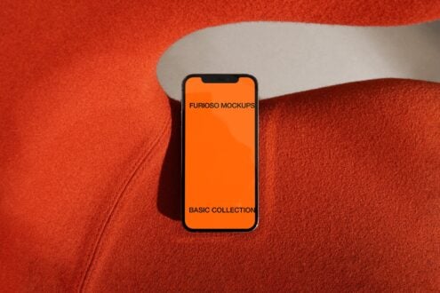 Mobile device on red fabric showing orange interface mockup