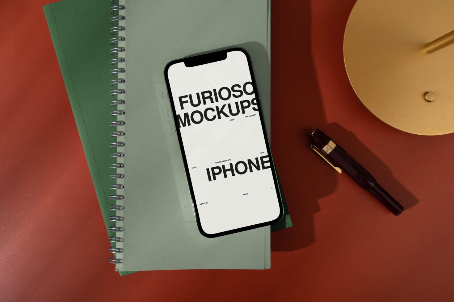 Blank phone screen on green notebook with pen, lamp, mixed color background
