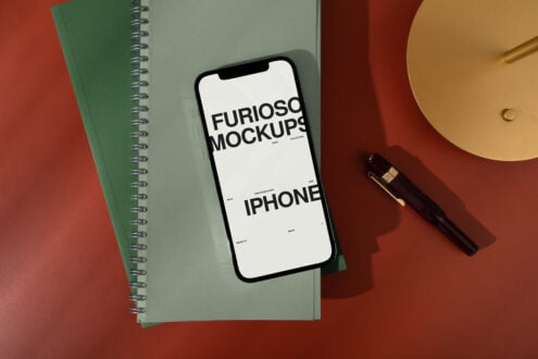 Blank phone screen on green notebook with pen, lamp, mixed color background