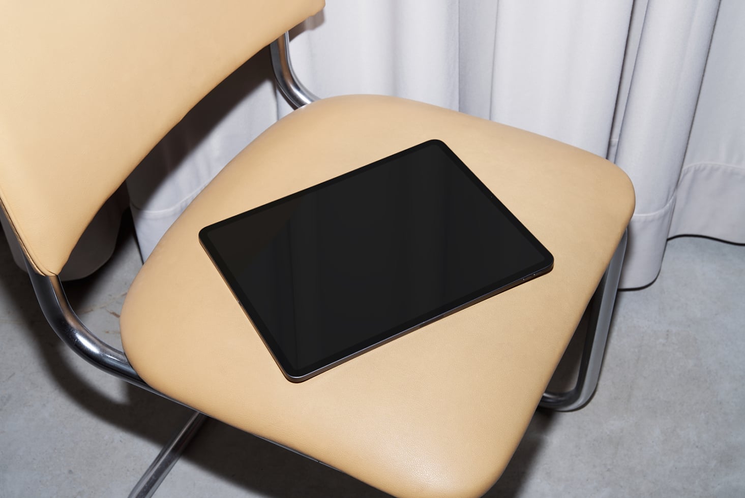 Tablet with black screen sitting on cream colored modern office chair