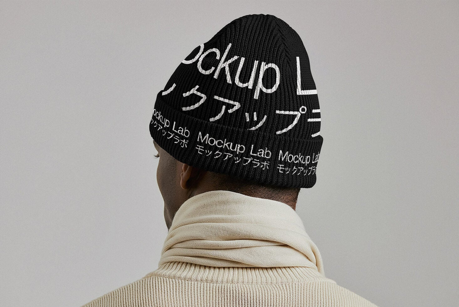 Back view of person in cream turtleneck wearing all black knit beanie
