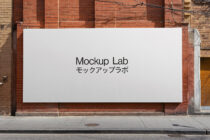 White rectangular billboard on red brick wall with Mockup Lab bilingual text