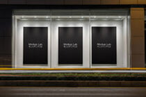 Lit storefront with three black poster frames in modern glass storefront