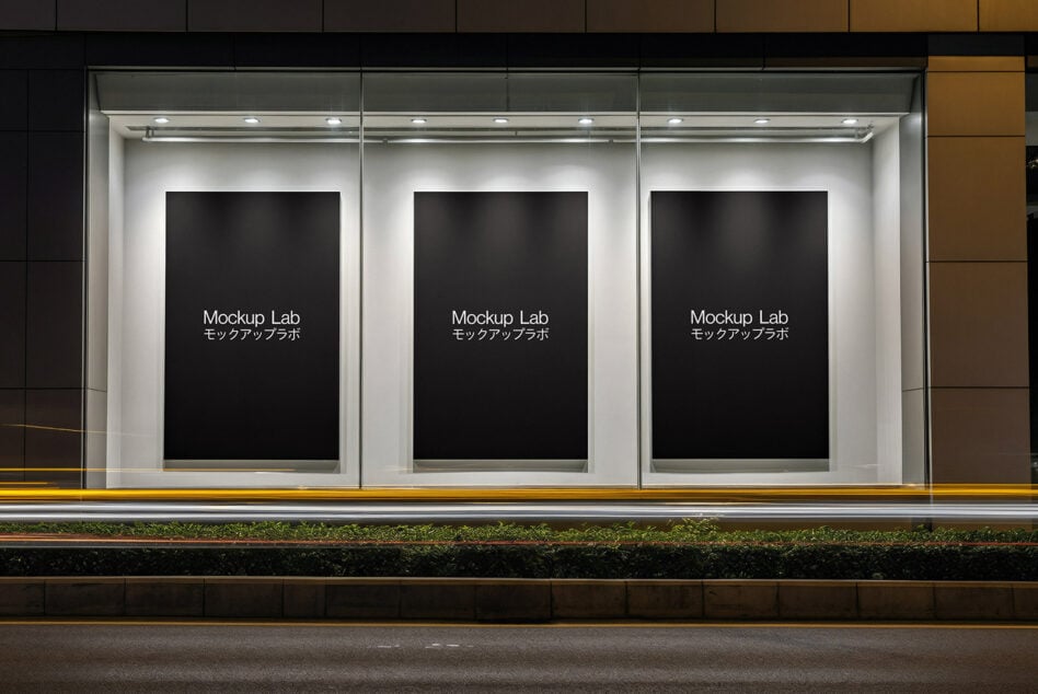 Lit storefront with three black poster frames in modern glass storefront