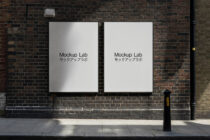Two white poster frames mounted on brick wall with sunlight casting shadows