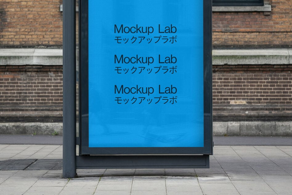 Street bus shelter displaying blue poster with text on urban brick wall