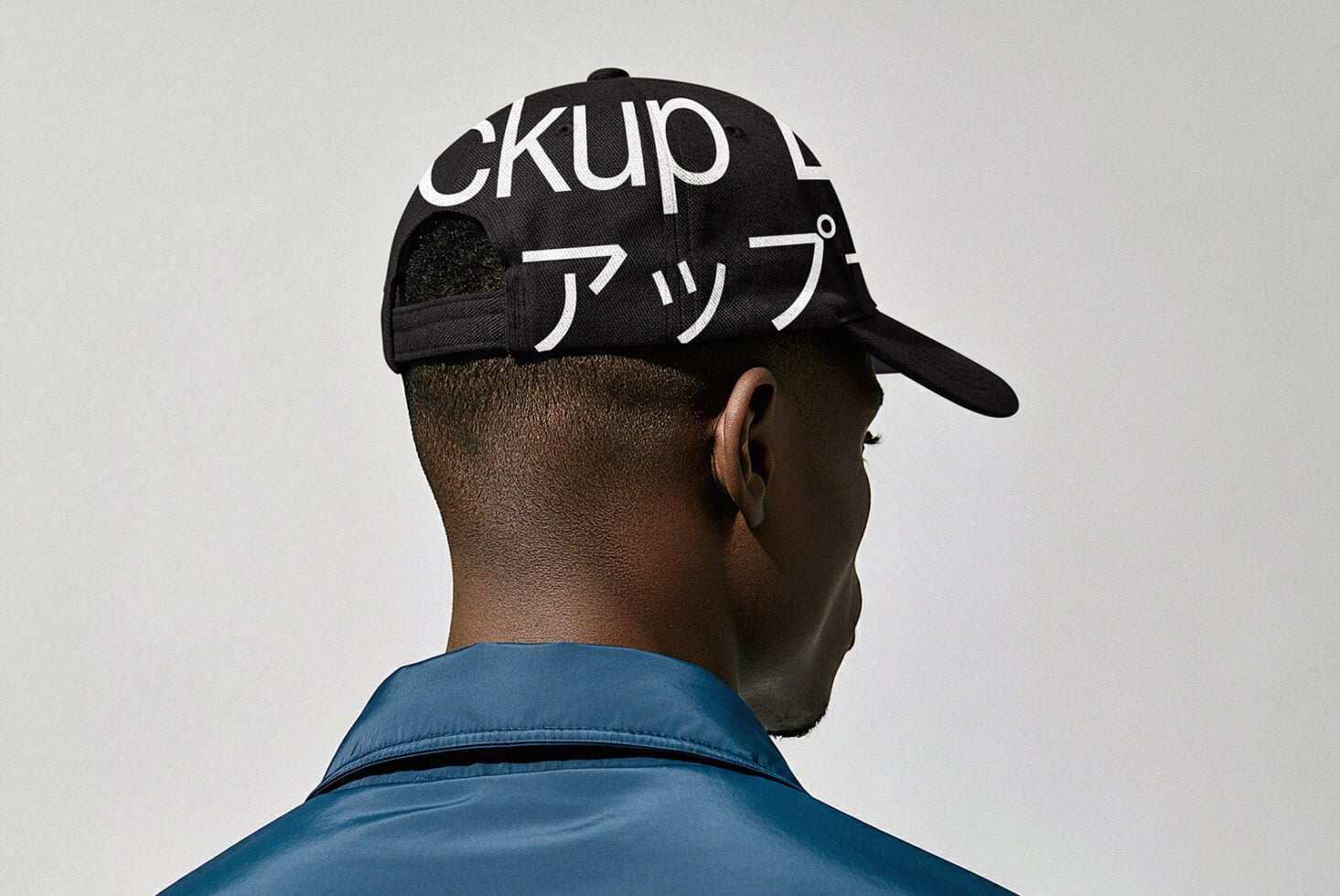 Back view of person wearing black baseball cap with white Japanese katakana text
