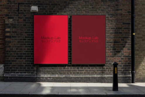 Two crimson red posters side by side on weathered dark brick building facade