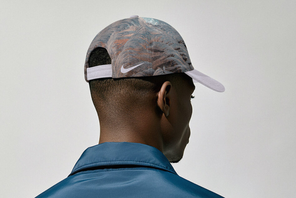 Back view of person wearing patterned baseball cap with white swoosh over blue jacket