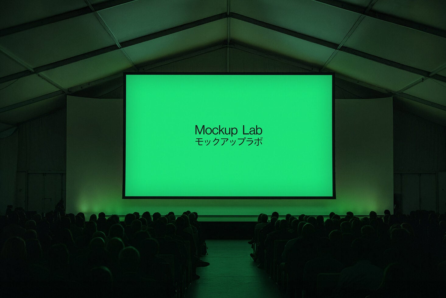 Theater screen displaying text on bright green with silhouetted audience seated below