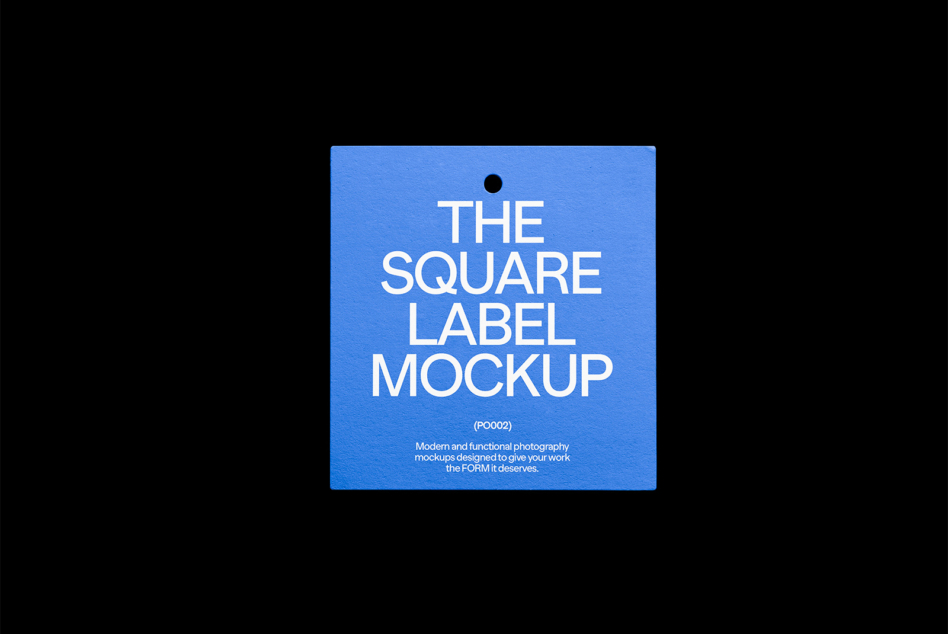 Square blue hanging product tag with hole punch against dark background
