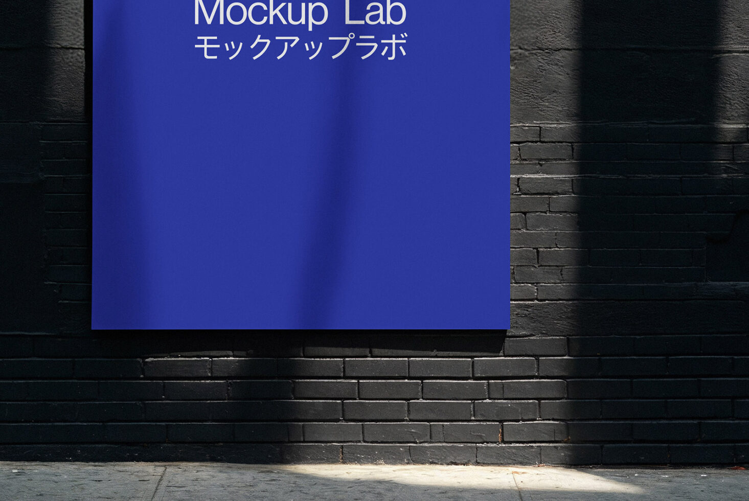 Vertical blue sign mounted on dark brick wall with dramatic shadow lines