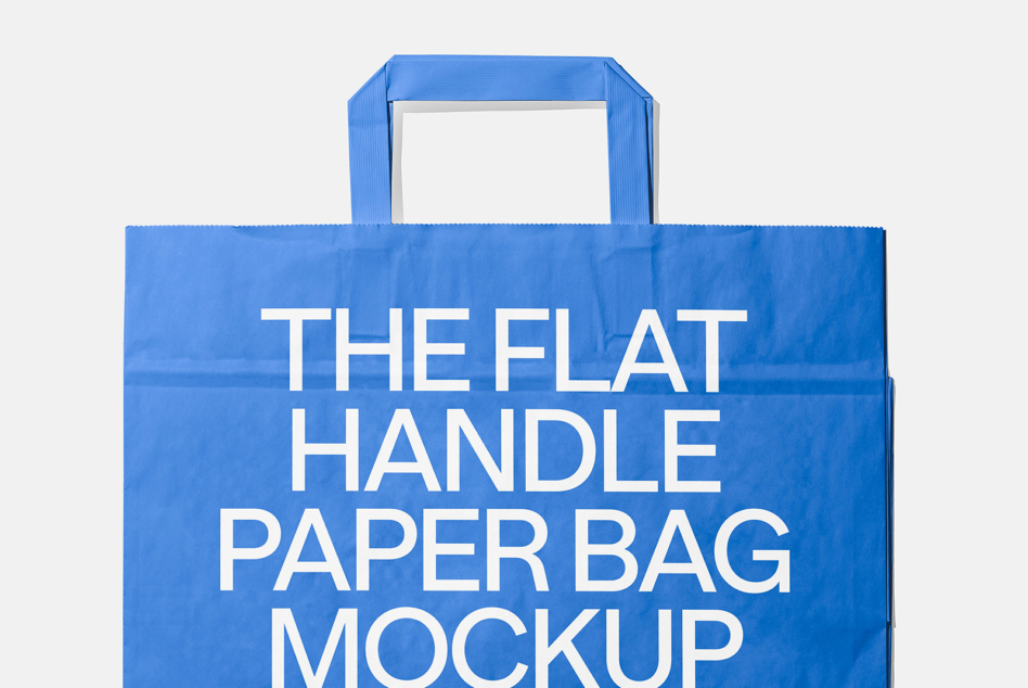 Blue paper shopping bag with flat handles on light gray background mockup