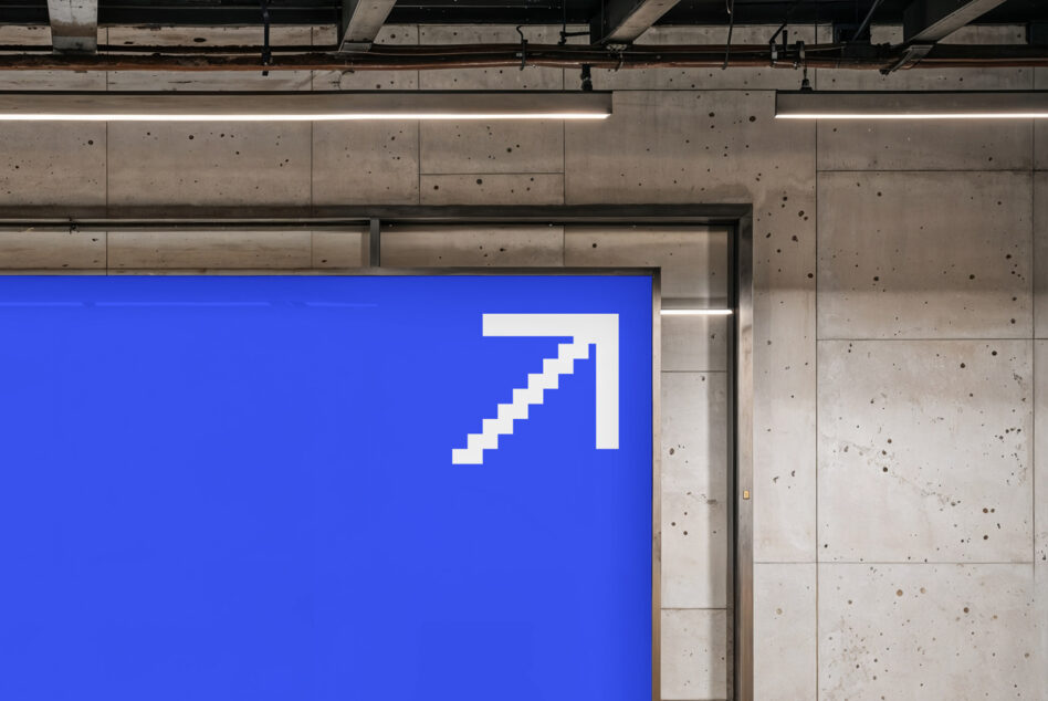Blue billboard mockup mounted on concrete wall with pixelated arrow design
