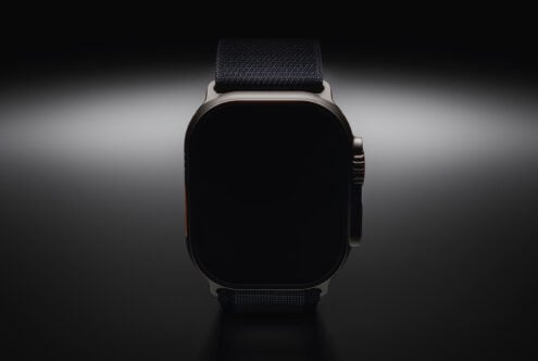 Smartwatch with black strap, blank screen, front view on gray background