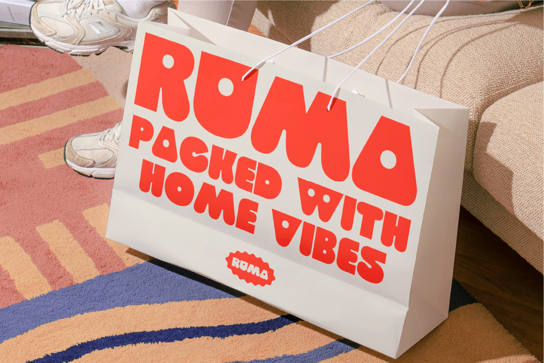 White shopping bag with red ROMA Pocked With Home Vibes text on colorful rug