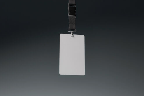 Blank white vertical badge mockup attached to dark fabric lanyard