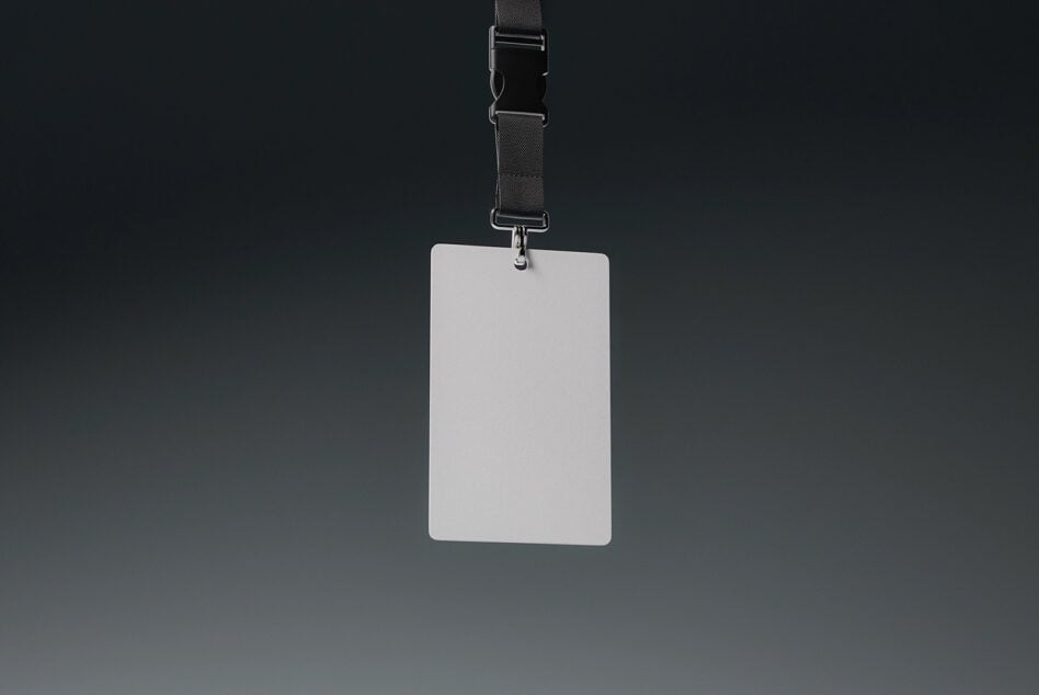 Blank white vertical badge mockup attached to dark fabric lanyard