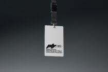 Clean white credential card with metal clasp on black adjustable strap