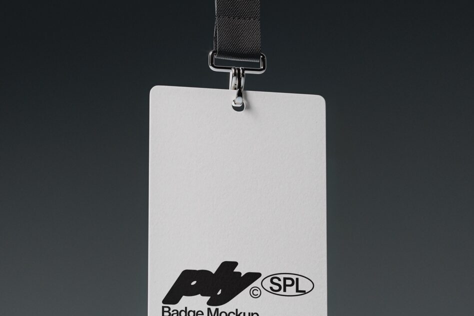 White ID badge hanging from black lanyard with silver metal clip