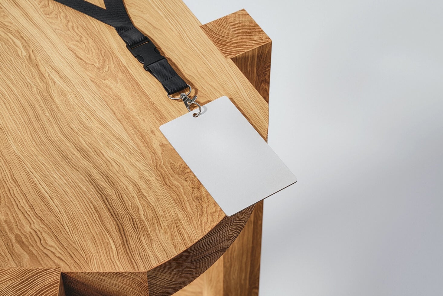 Empty white badge template on black strap draped over wooden block