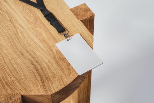 Empty white badge template on black strap draped over wooden block
