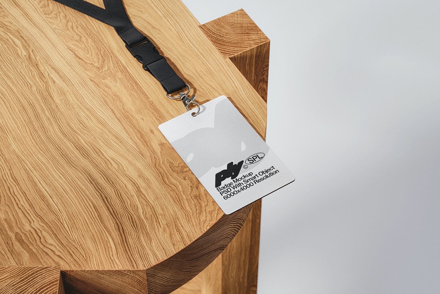 Badge mockup with printed text on wooden surface beside black lanyard clip