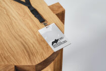 Badge mockup with printed text on wooden surface beside black lanyard clip