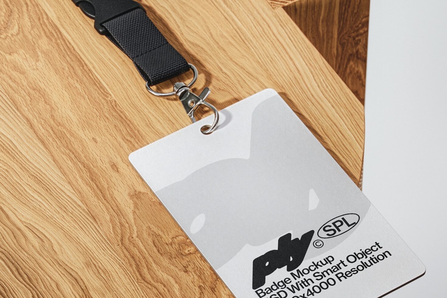 Blank ID badge mockup hanging on black lanyard against wooden surface