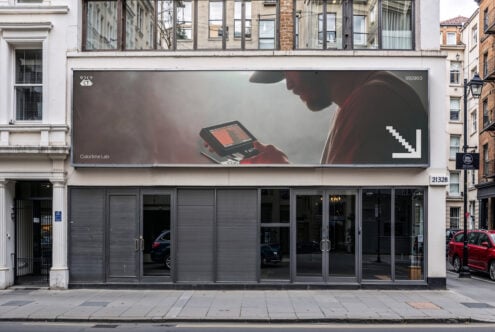 Large billboard mockup on storefront showing person with device in warm tones