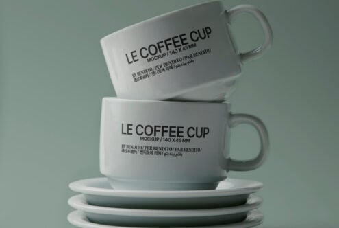 Stacked ceramic mugs with Le Coffee Cup branding on sage green background