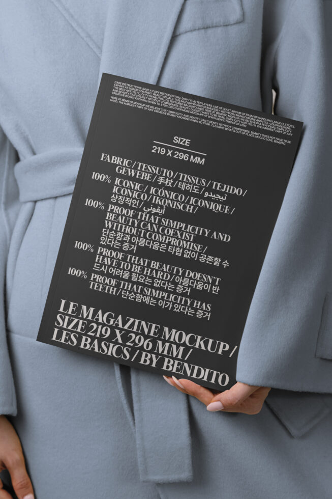 Black magazine held in hands against gray blazer, white typography visible