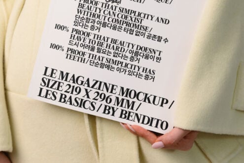 Magazine mockup on cream fabric, held by hand with manicured nails