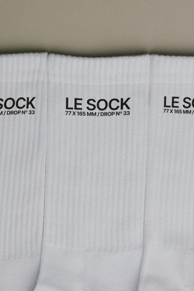 Stack of white ribbed socks with black Le Sock label showing 77 x 165 mm drop number 33