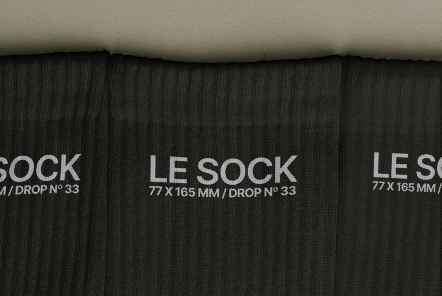 Overhead shot of black ribbed socks with white Le Sock label, drop number 33 visible
