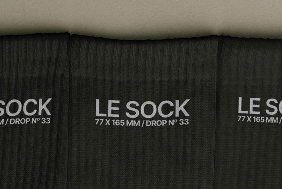 Overhead shot of black ribbed socks with white Le Sock label, drop number 33 visible
