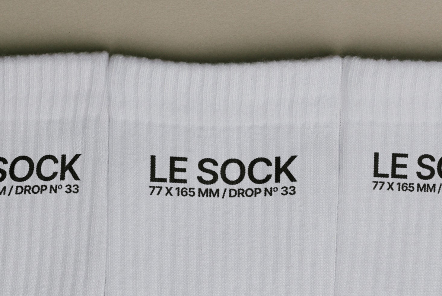 Overhead shot of white ribbed socks with black Le Sock label, drop number 33 visible