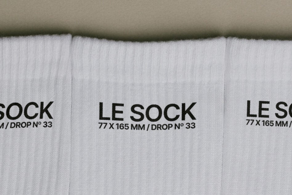 Overhead shot of white ribbed socks with black Le Sock label, drop number 33 visible