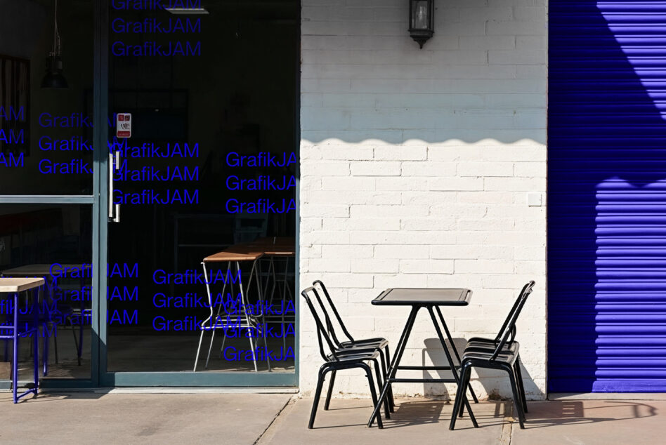 Storefront with blue neon text, black metal chairs, white brick