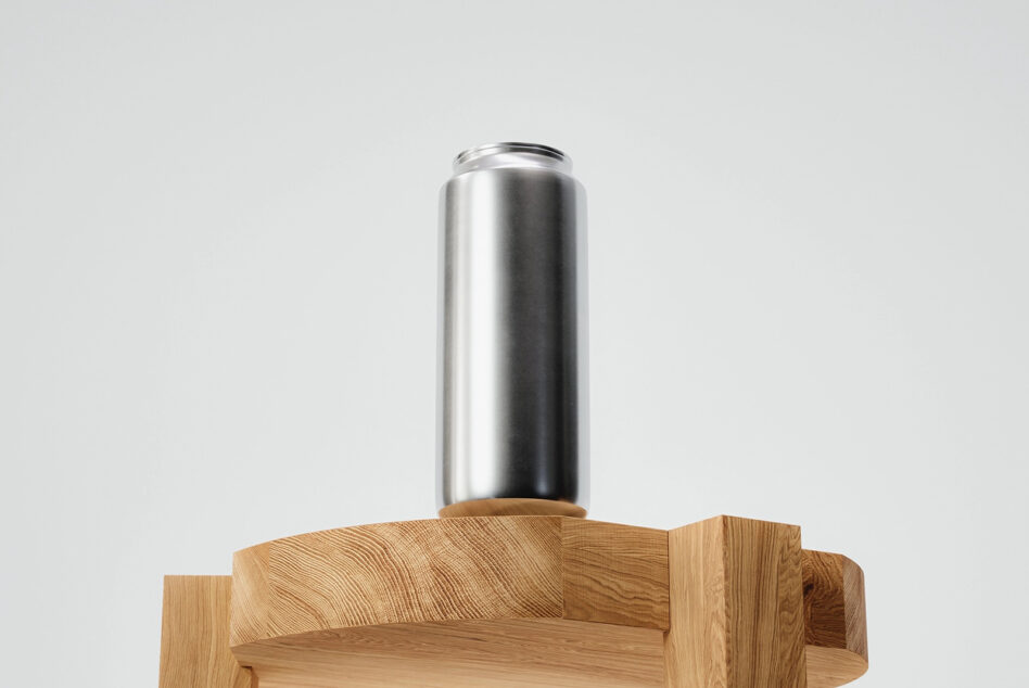 Tall metallic can sitting on carved wooden platform against neutral backdrop