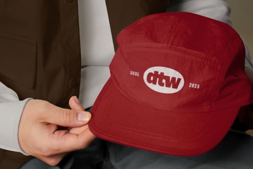 Red baseball cap with Seoul, ROMA logo worn by person in white shirt